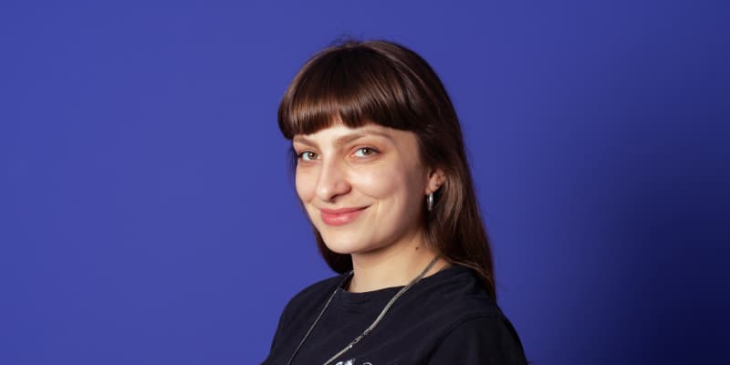 Porträt einer lächelnden Frau vor blauem Hintergrund