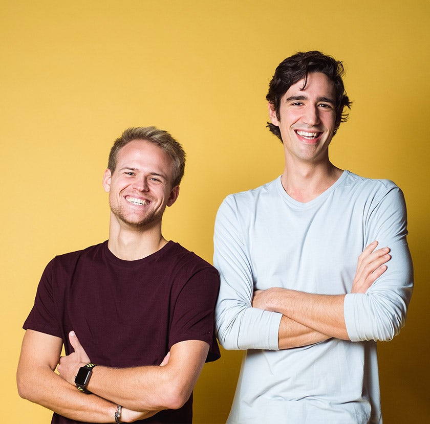 Two men standing and smiling - yellow background