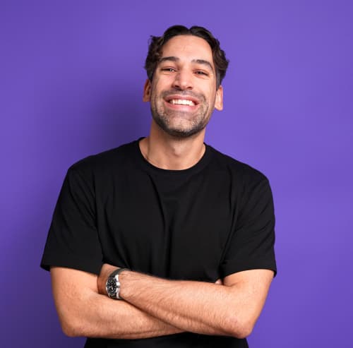 Lächelnder Mann in schwarzem T-Shirt vor violettem Hintergrund