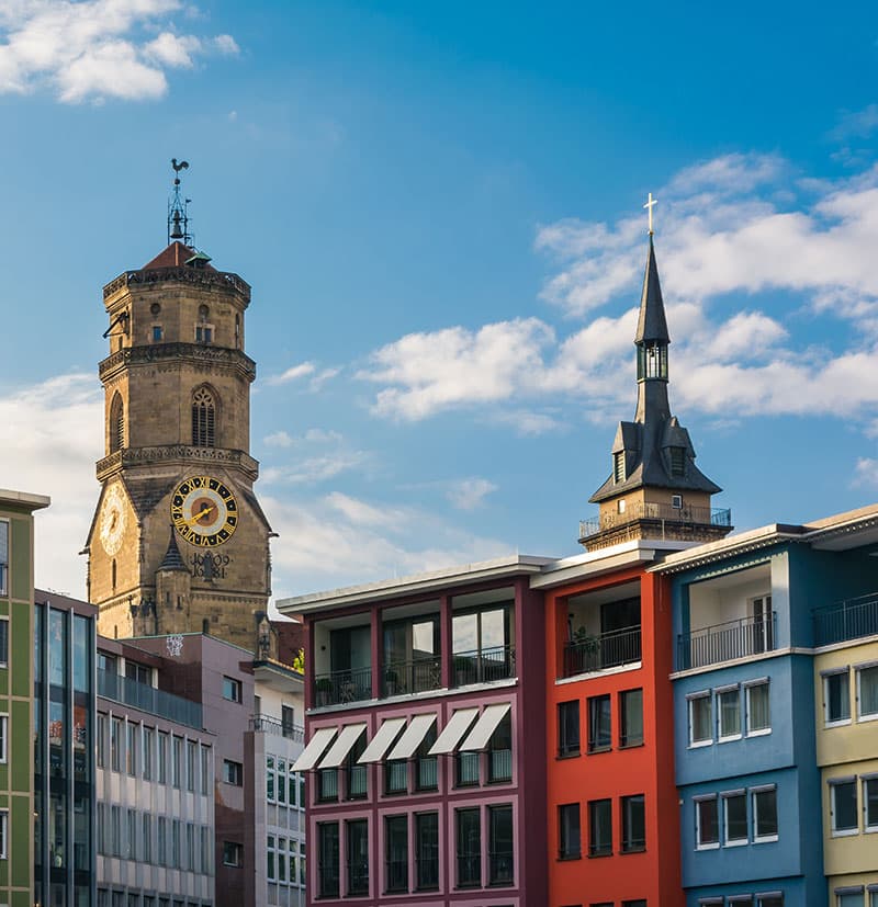 Historische Turmuhr und Kirchturm über bunten Gebäuden