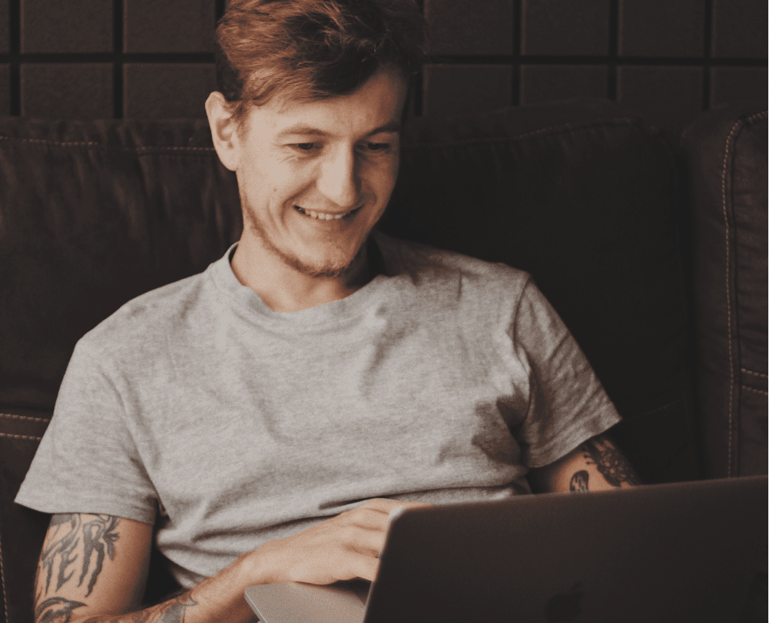 Man smiling while using a laptop.