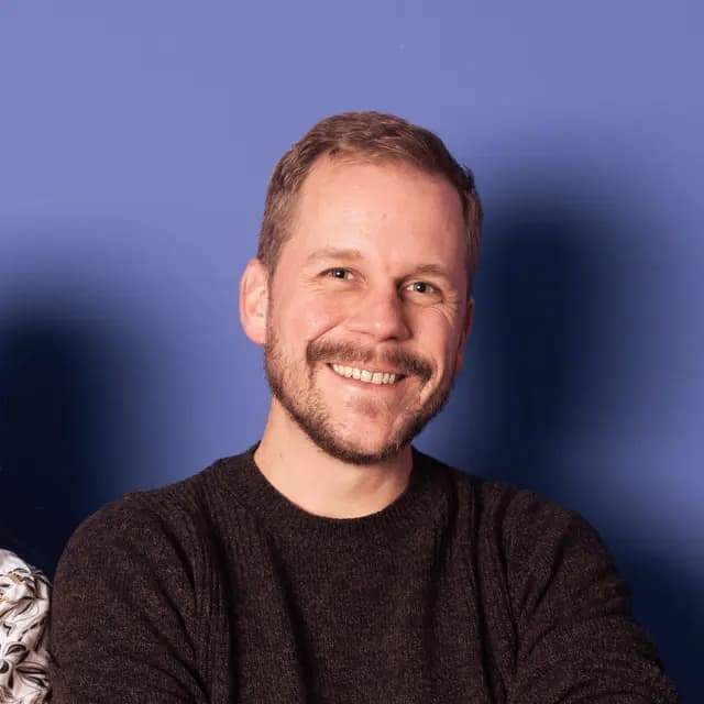 Lächelnder Mann in weißem T-Shirt vor grauem Hintergrund