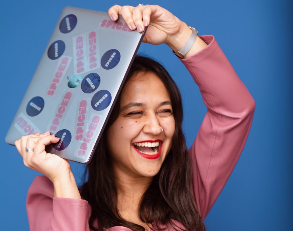 Woman holding Spiced computer in the air smiling