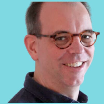 Porträt eines lächelnden Mannes mit Brille vor blauem Hintergrund