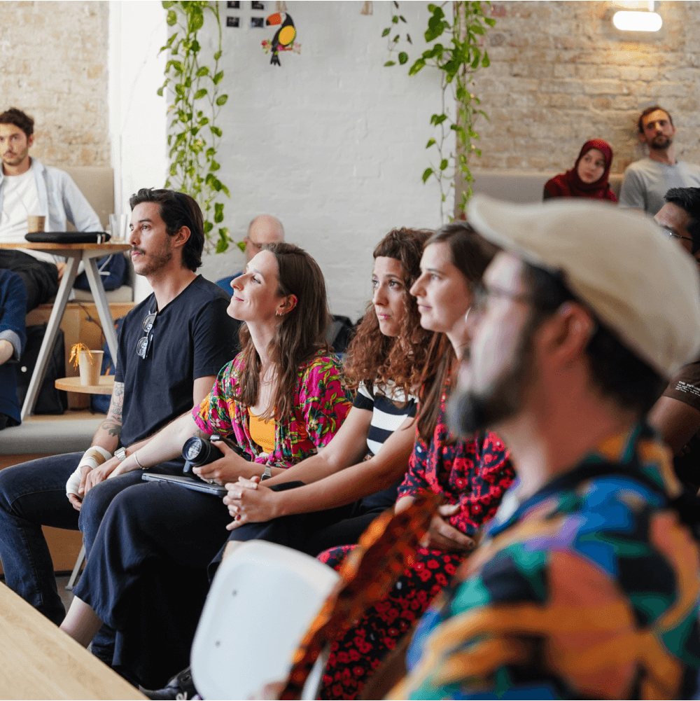 Menschen hören aufmerksam bei einer Veranstaltung in einem gemütlichen Raum zu.