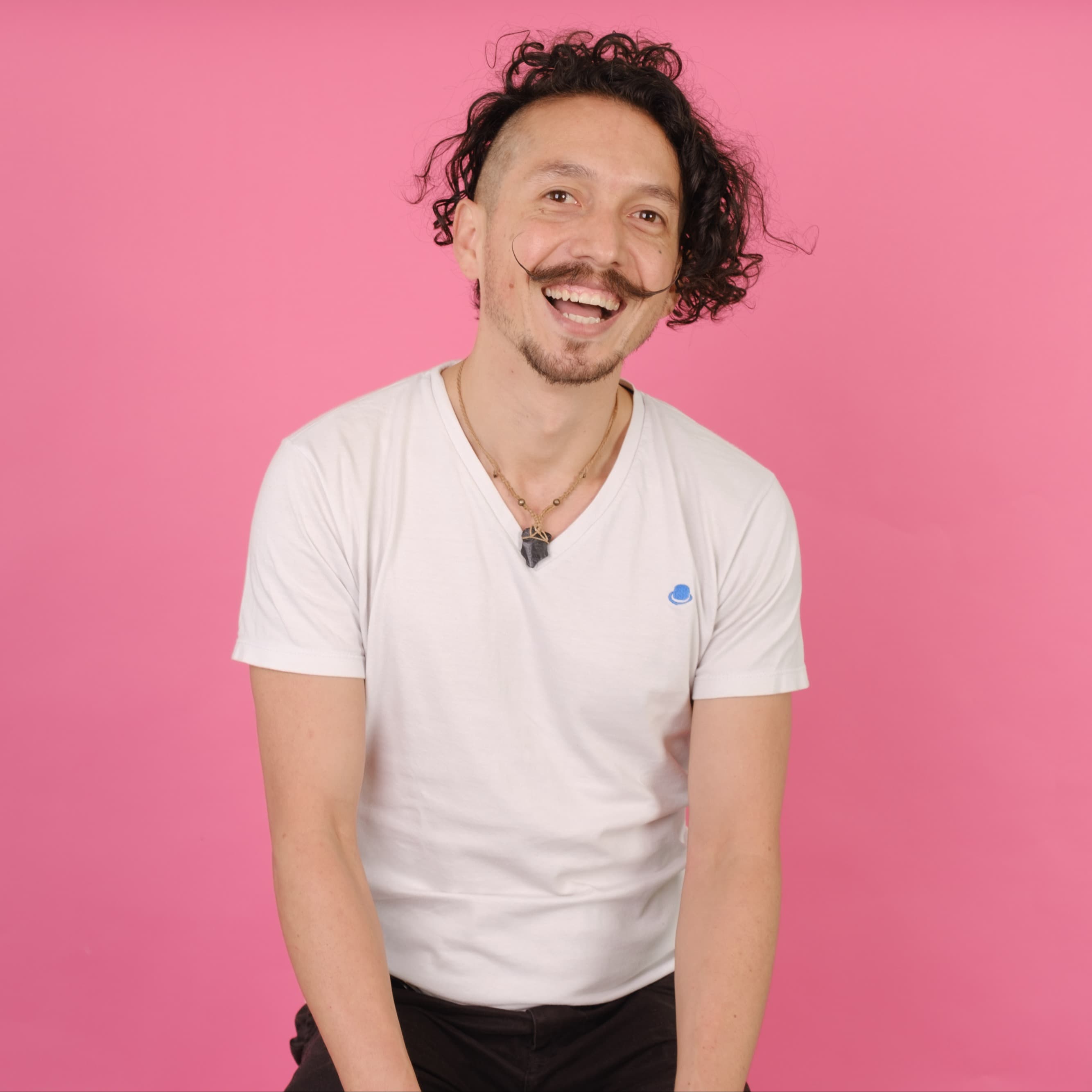 LĂ€chelnder Mann mit Schnurrbart vor pinkem Hintergrund