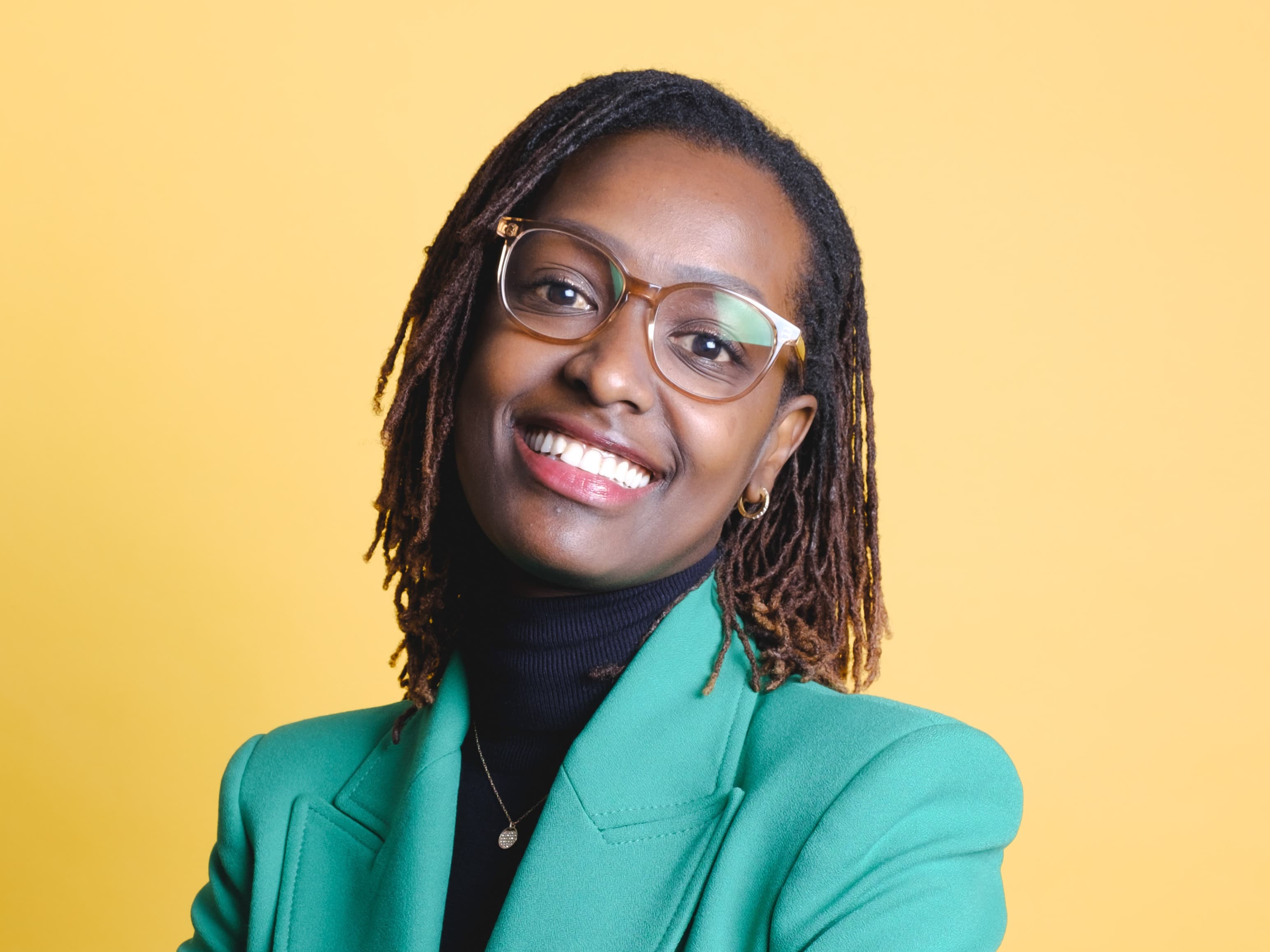 Portrait of a smiling woman with glasses against yellow background