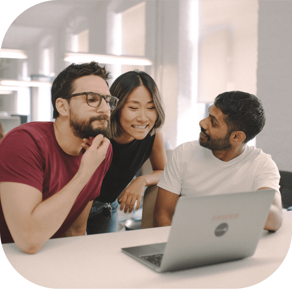 Drei Personen schauen gemeinsam auf einen Laptop.