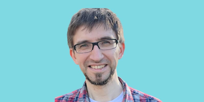 Man with glasses and checkered shirt against blue background