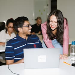 Two people working together on a laptop in an office.