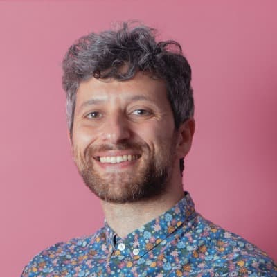 Porträt eines lächelnden Mannes vor rosa Hintergrund